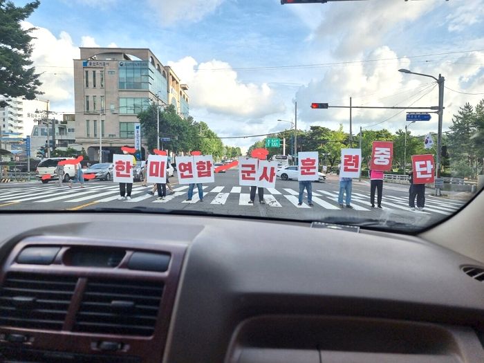 도로 한복판 횡단보도에 서서 “한미연합 군사 훈련 중단” 요구하는 시위대들
