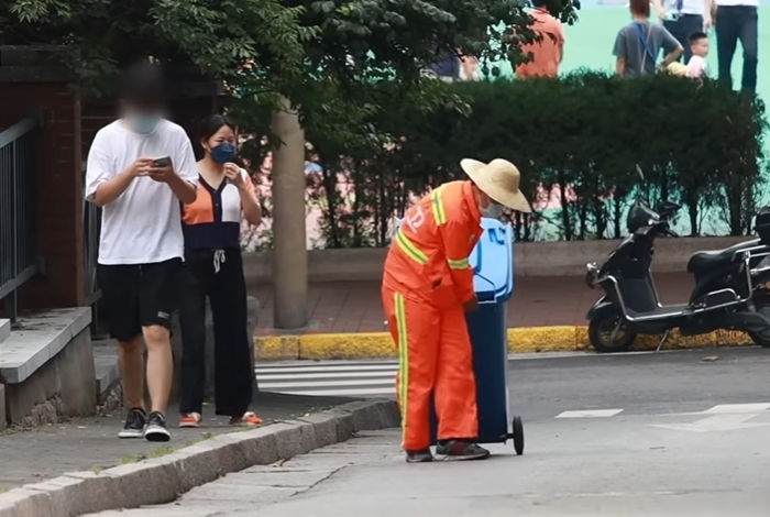 청년 청소부가 냄새나는 쓰레기통 옮기니까 옆에서 스마트폰 하던 여성이 한 행동 (영상)