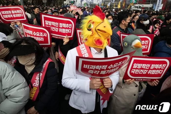 3일 서울 영등포구 여의대로에서 열린 '의대정원 증원 및 필수의료 패키지 저지를 위한 전국 의사 총궐기 대회'에서 한 의사 가운을 입은 참석자가 닭의 탈을 쓰고 손팻말을 들고 있다. / 뉴스1