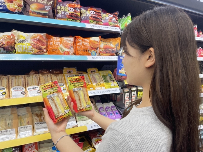 [사진자료2] GS25에서 모델이 보이 그룹 NCT DREAM 협업 상품 '아이돌컴백샌드위치'를 바라보고 있다.jpg