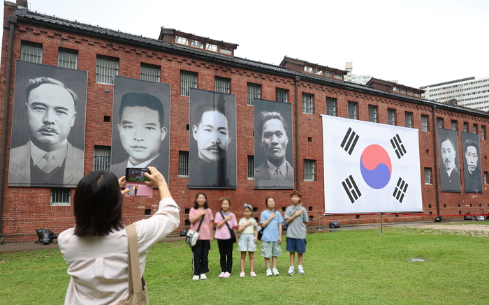 제80주년 광복절을 하루 앞둔 14일 서울 서대문형무소역사관을 찾은 어린이들이 독립운동가들의 모습을 담은 현수막을 배경으로 기념촬영을 하고 있다. 2025.8.14/뉴스1