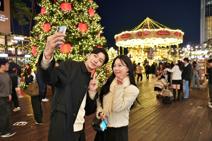 2. [롯데백화점] 롯데타운 잠실 '초대형 크리스마스 트리'와 '크리스마스 마켓'에서 '2층 회전목마'를 배경으로 사진을 찍는 모델.JPG