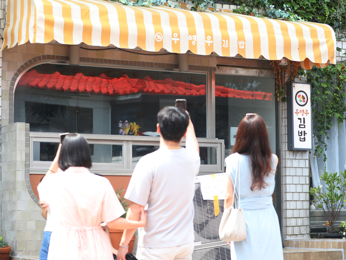 경기 수원시 팔달구 행궁동에 위치한 '이상한 변호사 우영우' 드라마 속 우영우 김밥집으로 나온 한 음식점에서 시민들이 우영우 김밥 간판 앞에서 인증샷을 찍고 있다. 2022.8.4/뉴스1
