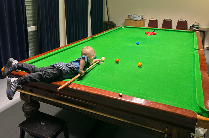 youngest-snooker-player-jude-lying-on-the-table.jpg